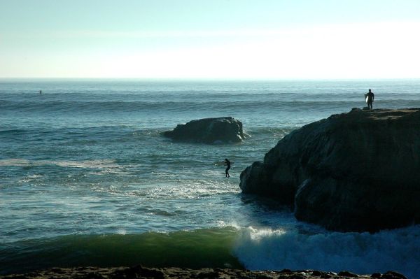Surfer jumps into the Pacific Ocean waves, Steamers Lane, Santa Cruz, California, USA